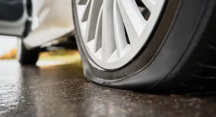 Close-up of a flat tire on a wet road